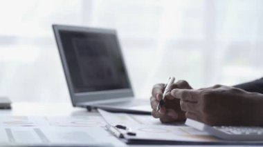 Bilgisayarda çalışan başarılı genç işadamı, 4K video 'da, kafede oturmuş, bilgisayarla iletişim kuran grafiği gösteriyor.