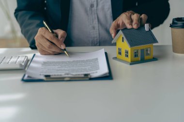 Emlakçı veya banka memuru evrak ve dizüstü bilgisayarla çalışarak ev satın alma sözleşmesi veya kredi faizi ve faiz oranına sahip müşteriye kredi faizini açıklar