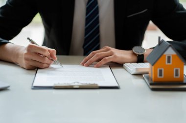 Emlakçı veya banka memuru evrak ve dizüstü bilgisayarla çalışarak ev satın alma sözleşmesi veya kredi faizi ve faiz oranına sahip müşteriye kredi faizini açıklar