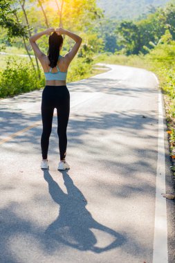 Parkta egzersiz yapan, koşan, plajda gezen Asyalı genç bir kadının görüntüsü. Açık hava fitness modelleriyle forma gir..