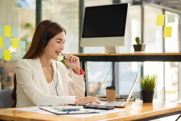 stock image young woman doing her work on computer and laptop making accounting analysis report real estate investment information Asian businesswoman talking on smartphone