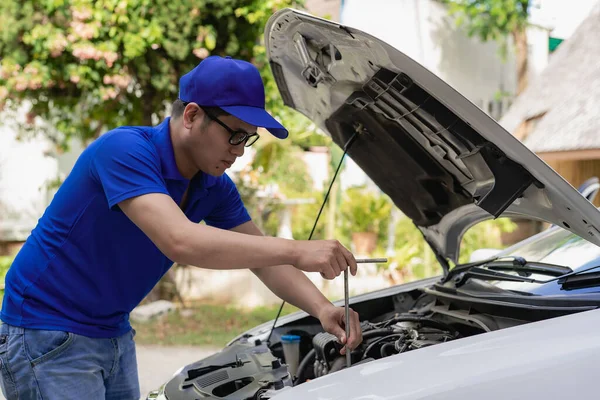 Home service mechanic checking car engine. Car service. Asian man opens his convertible and inspects his car. transportation concept