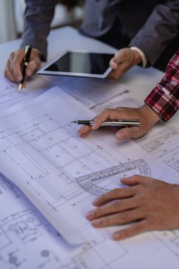 İş arkadaşları için mühendislik ekibi toplantısı ofis mühendisleri ve işyerindeki inşaat ve yenileme projelerini planlayan işçiler masasındaki planları tartışıyor ve gözden geçiriyorlar.