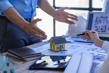 İş arkadaşları için mühendislik ekibi toplantısı ofis mühendisleri ve işyerindeki inşaat ve yenileme projelerini planlayan işçiler masasındaki planları tartışıyor ve gözden geçiriyorlar.