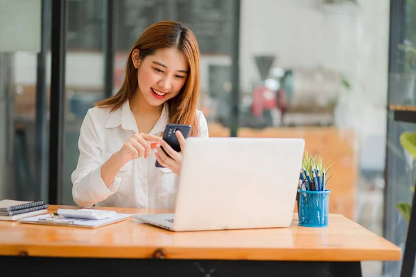 stock image Young successful young asian businesswoman working with smartphone and laptop to contact clients, financial concept