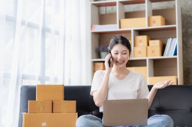 Asyalı kadın internetten sipariş alıyor. Satış, teslimat, pazarlama. Evden çalışırken dijital dizüstü bilgisayarları olan heyecanlı Asyalı genç girişimciler. Küçük işletme Başlangıç KOBİ