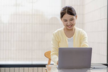 Dost canlısı ve mutlu Asyalı kadın dizüstü bilgisayar kullanıyor ve sohbet ediyor. Video konferansı, evde online iş görüşmesi, internet üzerinden özel ders..