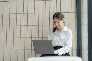 Dost canlısı ve mutlu Asyalı kadın dizüstü bilgisayar kullanıyor ve sohbet ediyor. Video konferansı, evde online iş görüşmesi, internet üzerinden özel ders..