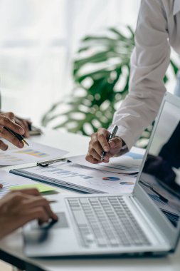 Finans grafik analizi, hesap makinesi ve bilgisayarla birlikte bütçe ve krediyi hesaplamak için kalem beyin fırtınası yapan bir grup iş adamı. Yatırım. Dikey resim.