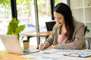 Dizüstü bilgisayarla çalışan Asyalı iş kadını, hesapla, analiz et, genç kadın, mali danışman, istatistiksel rapor hazırla, belgeleri incele, ofisteki mali tablolara bak.