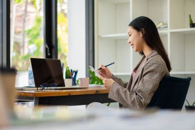 Dizüstü bilgisayarla çalışan Asyalı iş kadını, hesapla, analiz et, genç kadın, mali danışman, istatistiksel rapor hazırla, belgeleri incele, ofisteki mali tablolara bak.