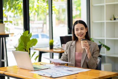 Dizüstü bilgisayarla çalışan Asyalı iş kadını, hesapla, analiz et, genç kadın, mali danışman, istatistiksel rapor hazırla, belgeleri incele, ofisteki mali tablolara bak.