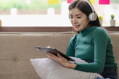 Tablet kullanan, tablet kullanan gülümseyen Asyalı kadın dizüstü bilgisayarındaki filmleri izle, çalış, blog yap, rahatla, çevrimiçi aktivitelerden zevk al. Bilgisayarla çalışmak çevrimiçi konuşma etkinlikleri yapmak