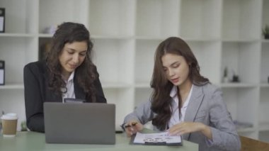 İki iş kadını, şirket brifinginde grafik ve çizelge içeren belgeleri ve başarılı takım çalışmasını tartışıyor. 4k video