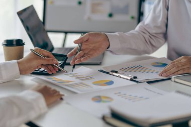 Bir grup Asyalı iş adamı bilgisayar ekranındaki grafiklere, indekslere ve rakamlara bakarak finansal raporla analiz konseptine yatırım yapma planını tartışıyor.