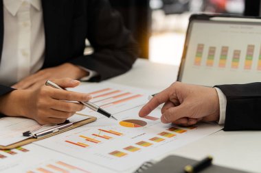 Bir grup Asyalı iş adamı bilgisayar ekranındaki grafiklere, indekslere ve rakamlara bakarak finansal raporla analiz konseptine yatırım yapma planını tartışıyor.