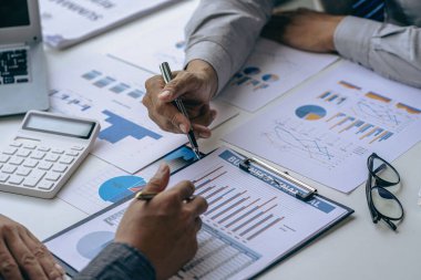 Bir grup Asyalı iş adamı bilgisayar ekranındaki grafiklere, indekslere ve rakamlara bakarak finansal raporla analiz konseptine yatırım yapma planını tartışıyor.