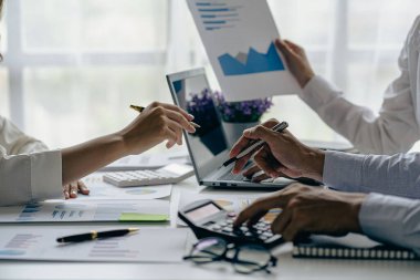 Bir grup Asyalı iş adamı bilgisayar ekranındaki grafiklere, indekslere ve rakamlara bakarak finansal raporla analiz konseptine yatırım yapma planını tartışıyor.