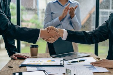 Modern bir konferans salonunda müşterilerle tokalaşan iş adamları takım lideri, birbirlerini selamlamak için grupla tanışır. Güven ve saygı gösteren el sıkışma, finansal muhasebe kavramı