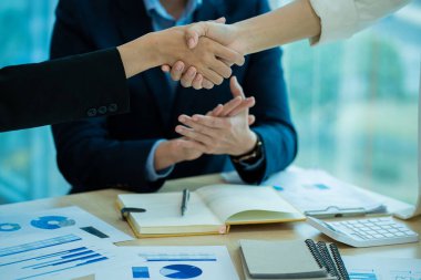 Modern bir konferans salonunda müşterilerle tokalaşan iş adamları takım lideri, birbirlerini selamlamak için grupla tanışır. Güven ve saygı gösteren el sıkışma, finansal muhasebe kavramı