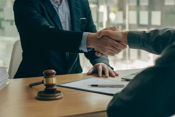 Lawyer shaking hands with client after agreement Gavel Justice hammer on wooden table with judge and client shaking hands after advice in courtroom, notary service concept