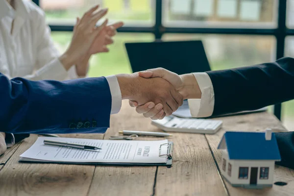Buyers and real estate agents agree to trade in handshake to rent or buy a home after signing a contract. Businessman congratulates buyer after agreeing to insure and buy house project, insurance