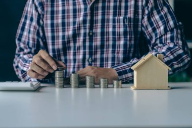 Erkek eller yığınla para istifliyor. Tahta zeminde, hesaplamalarla ev finansmanlarıyla birlikte büyüyen grafikler gibi. Faiz oranı ve vergi, bankacılık kavramı