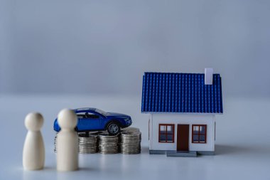 Beyaz arka planda izole edilmiş bozuk para yığını olan model araba ve ev. Para yığını, gelecekteki tasarruf konsepti İş ve finansmanı yönetmeyi başarır.