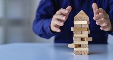 Risk yönetimi kavramları Eller 'in ufalanan tahta blokları korumaya çalışması kule işadamı dikkatle yüksek kuleye tahta bloklar yerleştirmesi ve yüksek tahta kuleyi savunması da çok riskliydi..