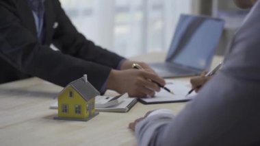 Emlakçılar ve alıcılar yeni ev sözleşmeleri imzalarlar ve müşterilerle el sıkışarak satın almakla ilgilendikleri mülklerin, konut projelerinin detaylarını açıklarlar..