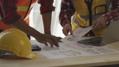 Mimar ve ustabaşı inşaat alanının planlarına bakıyor ve inşaatı planlıyor. Mühendisler çözüm üretmek için beyin fırtınası yapıyor. Başarılı bir geliştirme stratejisi planla.