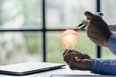 İş adamları konferans odasında enerji tasarrufu yapmak için ampul tutuyorlar.