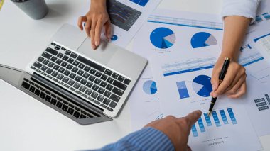 Finans müdürünün elleri masadaki, iş planındaki raporları analiz ediyor ve birçok grafiği dizüstü bilgisayar, hesap makinesi, kalem, üst görünüm ile analiz ediyor..