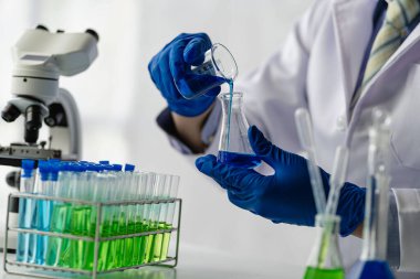 Biyoloji ya da mikroskop ile cam tüpte kimyasal sıvıyla tıp laboratuvarı teknolojisi araştırması yapan bilim adamı. Laboratuvarda..