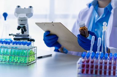 Biyoloji ya da mikroskop ile cam tüpte kimyasal sıvıyla tıp laboratuvarı teknolojisi araştırması yapan bilim adamı. Laboratuvarda..