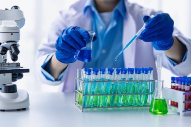 Biyoloji ya da mikroskop ile cam tüpte kimyasal sıvıyla tıp laboratuvarı teknolojisi araştırması yapan bilim adamı. Laboratuvarda..