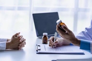 Doktor, klinikteki hastayla konuşuyor. Kadın hasta, hastane koltuğunda oturup doktorlara sağlık sorununu anlatıyor. Danışman konsepti.