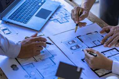 Bina planına işaret eden mühendis ve ofis inşaat tasarımı projesini çizmek ve ortaklarla işbirliği yapan yapı mühendisleri veya mimarlarla tanışmak için dizüstü bilgisayar kullanıyor..