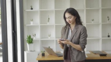 İş kadını cep telefonunu mesaj göndermek için kullanıyor. Güzel elleri olan genç bir kadın iş yerinde arkadaşıyla konuşuyor.