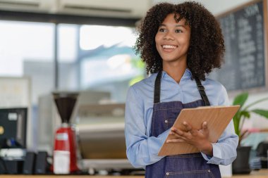Gülümseyen Afro-Amerikan kahveci kahve tezgahının arkasında durup müşteri, yiyecek ve içecek konseptini kabul ediyor.