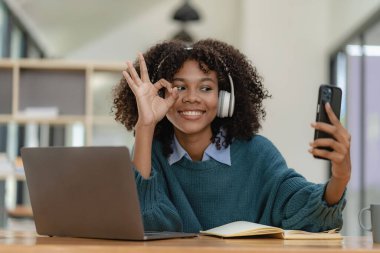 Not defterine dizüstü bilgisayarla yazı yazan Afrikalı Amerikalı bir kız. Çok çalışıyorum. İnternette çalışırken kulaklık takan bir kadın. Öğrenci kafede dil öğrenmek için heyecanlı.