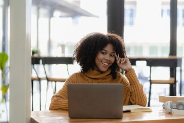 Not defterine dizüstü bilgisayarla yazı yazan Afrikalı Amerikalı bir kız. Çok çalışıyorum. İnternette çalışırken kulaklık takan bir kadın. Öğrenci kafede dil öğrenmek için heyecanlı.