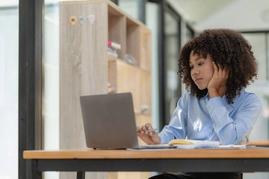 Genç mutlu başarılı iş kadını bilgisayarla çalışıyor ve analitik hesap makinesi ile ofisteki online toplantı konseptinde finansal grafik belgesi hesaplıyor.