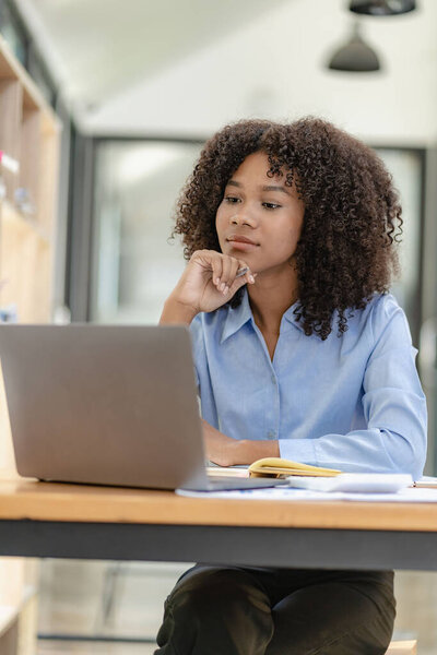 Young happy successful business woman working with laptop and calculating analytical calculator with financial graph document in office online meeting concept