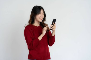 Asyalı uzun saçlı, elinde akıllı telefon tutan siyah kadın çok mutlu. Heyecanlı ve şaşırmış el hareketleri. Beyaz arka planda izole edilmiş stüdyo portresi.