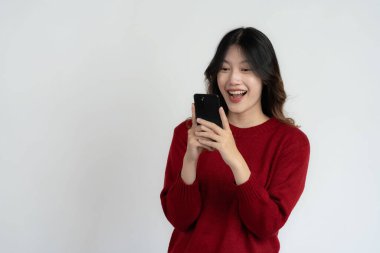 Asyalı uzun saçlı, elinde akıllı telefon tutan siyah kadın çok mutlu. Heyecanlı ve şaşırmış el hareketleri. Beyaz arka planda izole edilmiş stüdyo portresi.