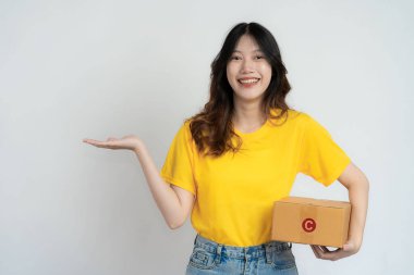 Genç Asyalı bir kadın beyaz arka planda güzel bir gülümseme ile bir kutu tutuyor. Çevrimiçi KOBİ iş ve dağıtım kavramı.