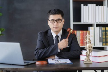 Asyalı erkek avukat çekiç ve teraziyle çalışıyor. Adalet Tanrıçası, kolluk kuvveti, hâkim çekici, davanın kanıtı olarak kabul edilen belgeler, online hukuk danışmanı..