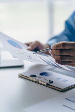 Businessman holding pen pointing to bar chart on company finance document, financial concept vertical image