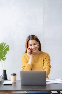 Happy Asian female employees working in modern large office company manager Professional businessman or employee using laptop talking on the phone. vertical image